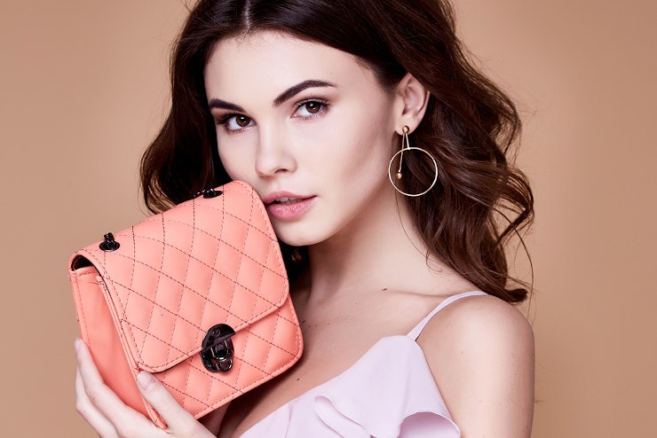 Junge Frau präsentiert Designerhandtasche