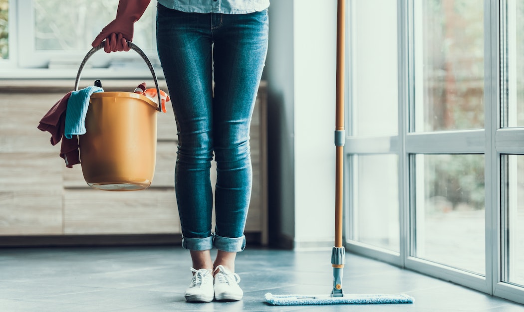 Junge Frau mit Wischmob und Putzeimer
