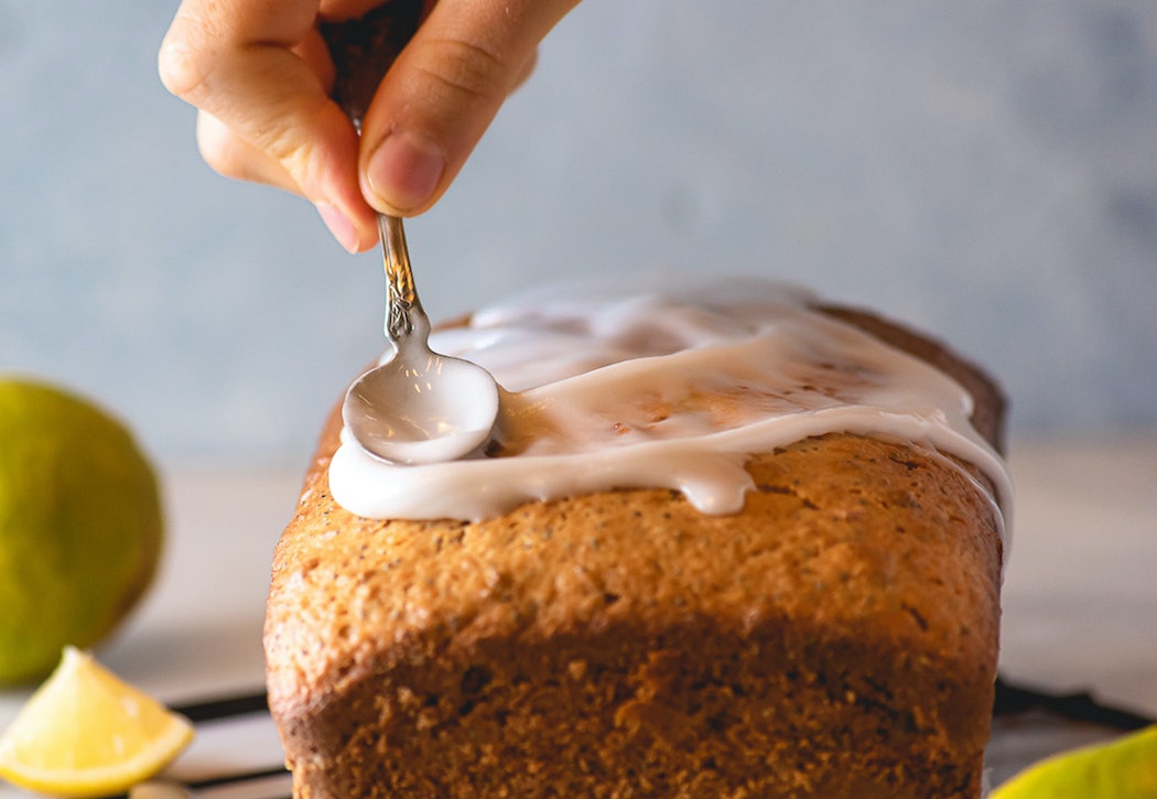 Glasur wird mit Löffel auf Zitronenkuchen verstrichen