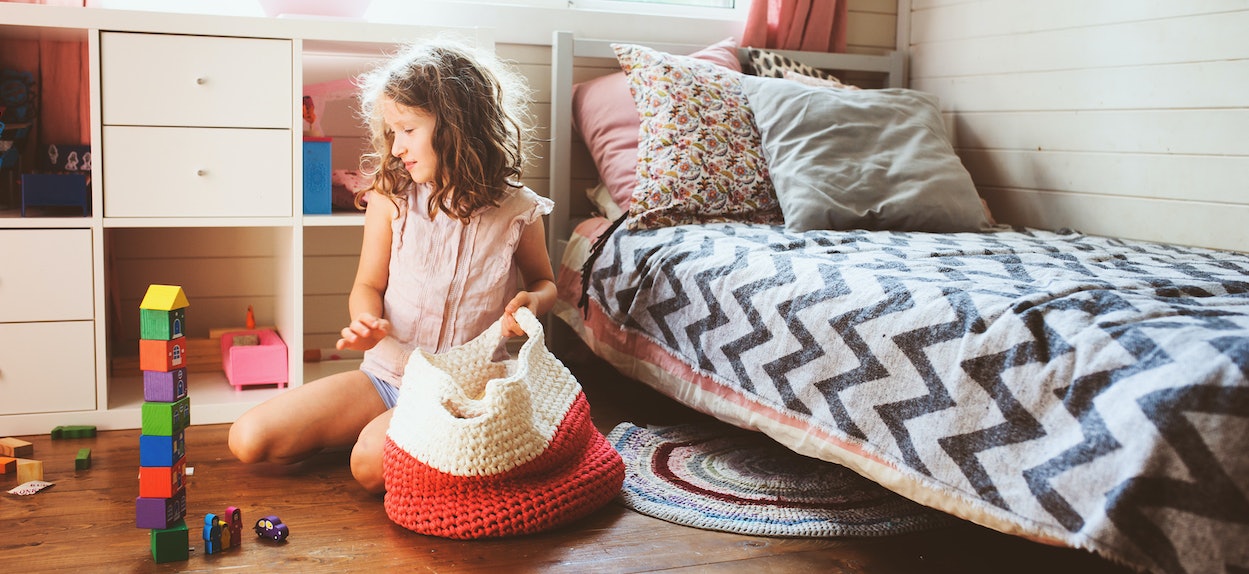 Kind packt Bausteine in Aufbewahrungskorb