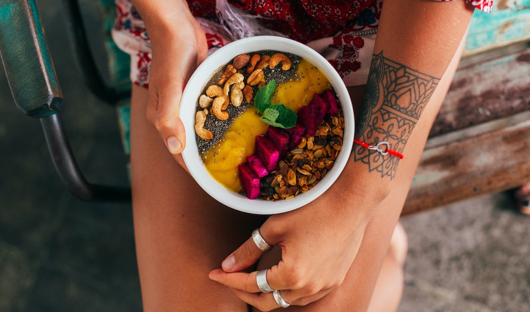 Junge Frau hält Schüssel mit gesundem Frühstück