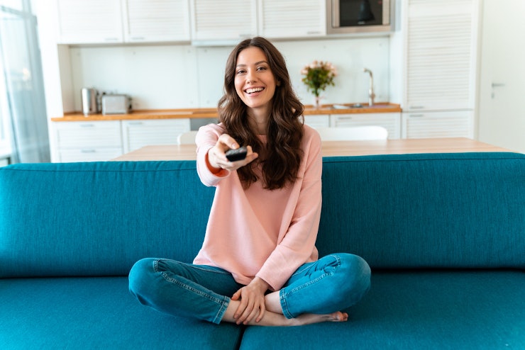 Glückliche Frau mit Fernbedienung in der Hand